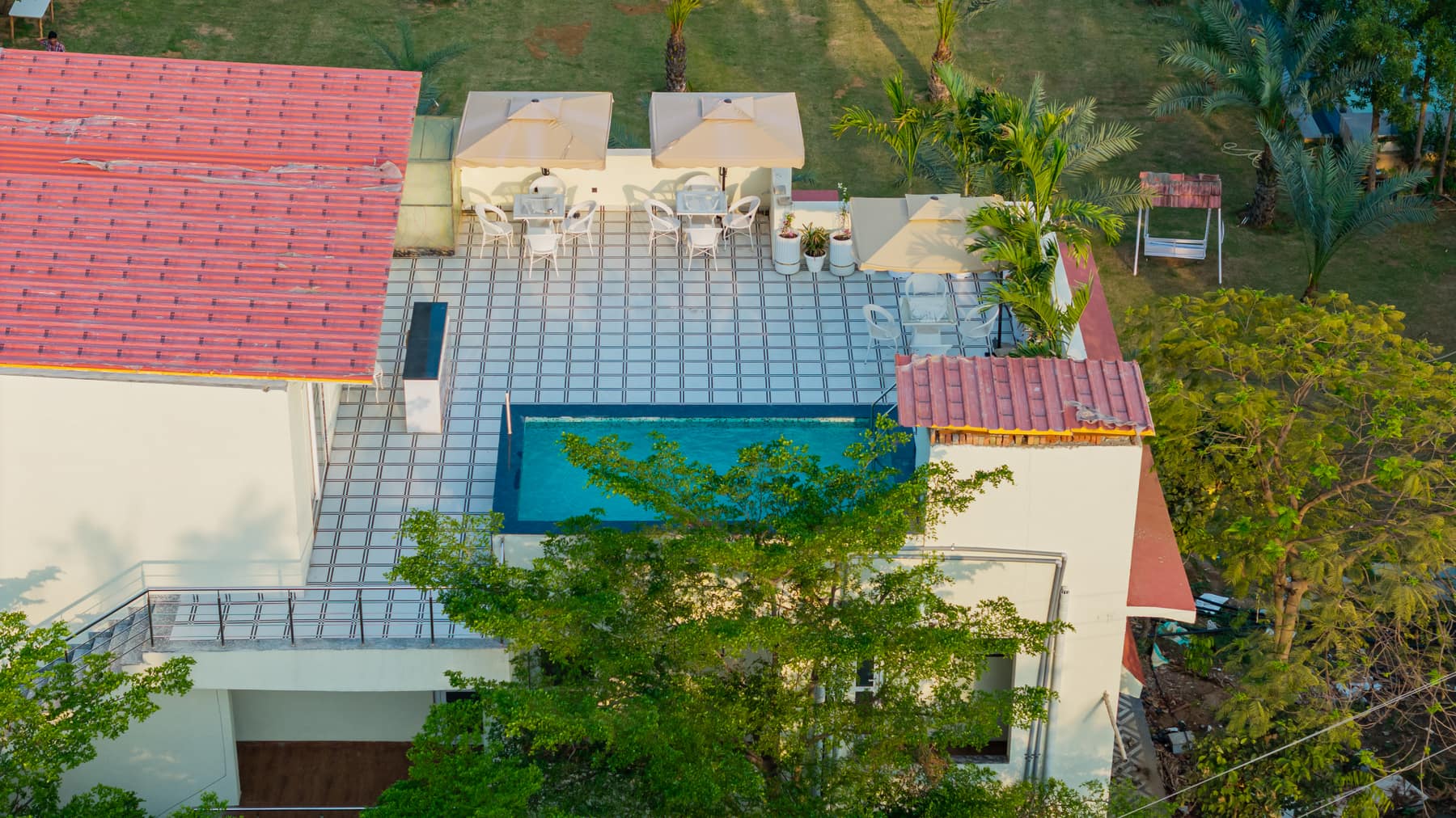 Aerial view of the villa rooftop terrace and pool amid palms and lawns