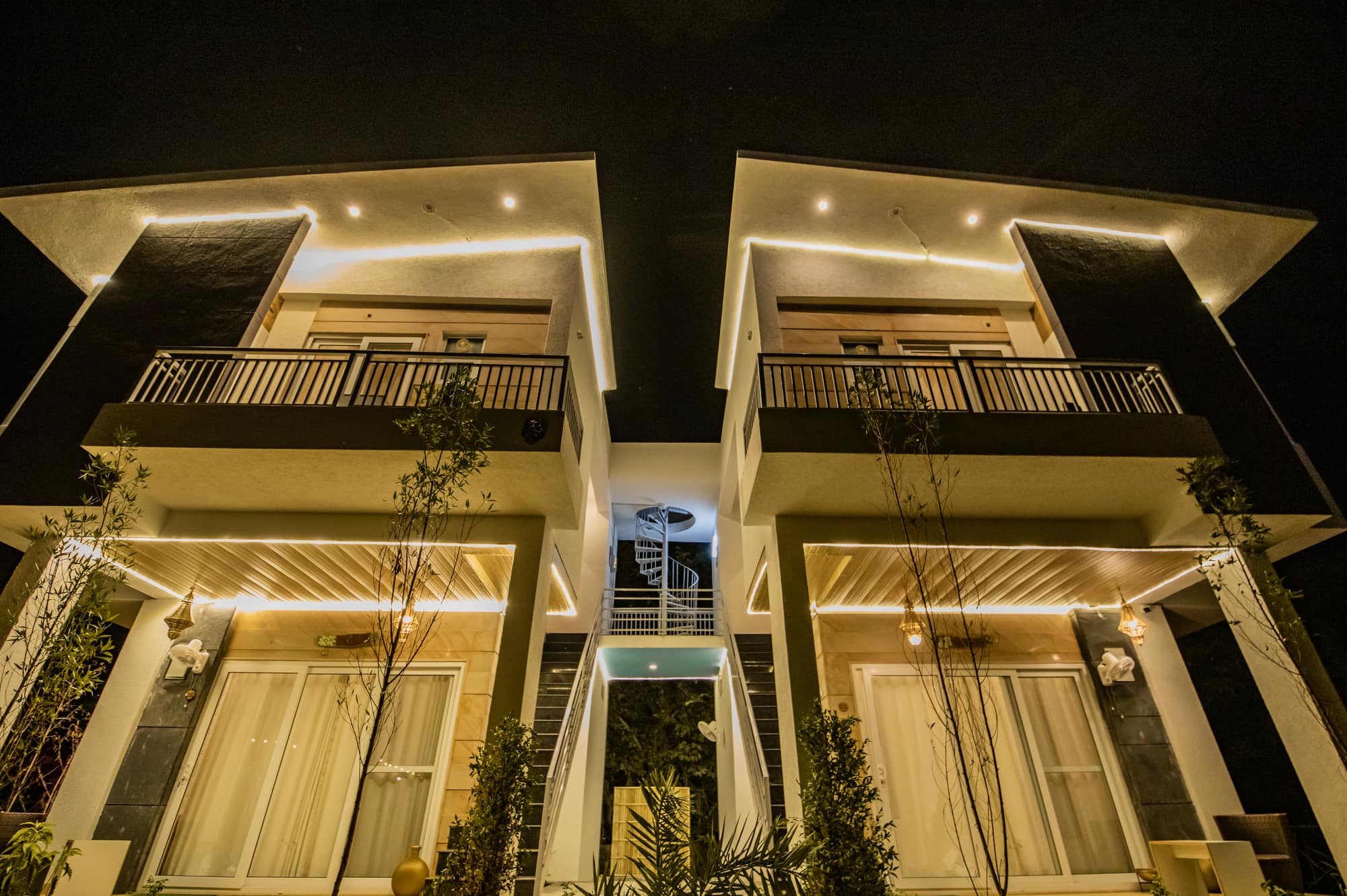 The twin villa at night, its balconies and eaves outlined in warm cove lighting