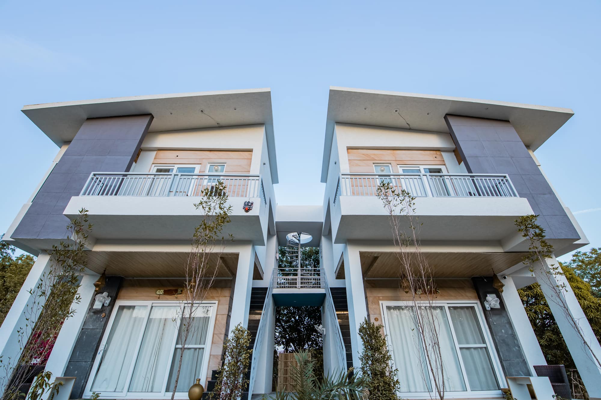 Lilly and Jasmine twin villa by day — mirrored white houses with balconies and a linking spiral stair
